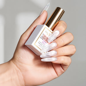 Hand with long pearly nails holding a gold capped Cre8tion Sheer Silver cat eye gel bottle by its box.