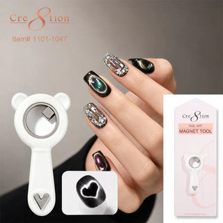 White bear shaped Cre8tion ring magnet beside a hand wearing black and chrome cat eye nails.