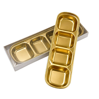 Two long gold Cre8tion spa trays with four compartments each, laid crossed on white.
