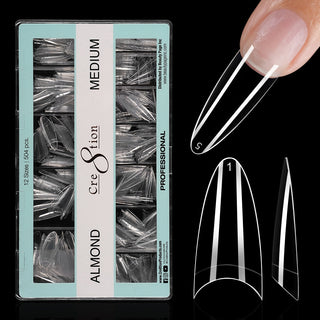 Open mint green box of clear Cre8tion Almond Medium tips on black, one tip fitted to a fingertip.