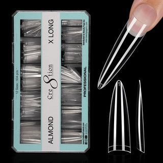 Open mint green box of clear Cre8tion Almond Extra Long tips on black, one tip fitted to a fingertip.