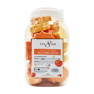 Clear jar of Cre8tion Autumn Spice pedicure soak bombs shaped as orange pumpkins and yellow maple leaves.