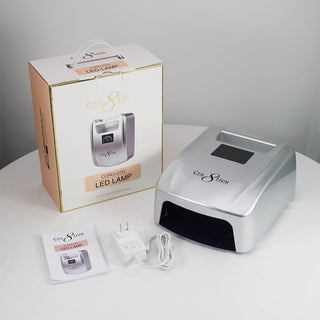 Silver Cre8tion cordless 36W LED lamp beside its retail box, with manual, adapter and cable.